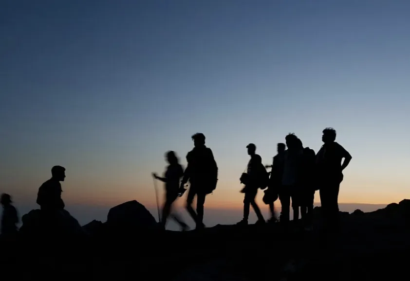 Group of hikers silhouetted against a dusk sky