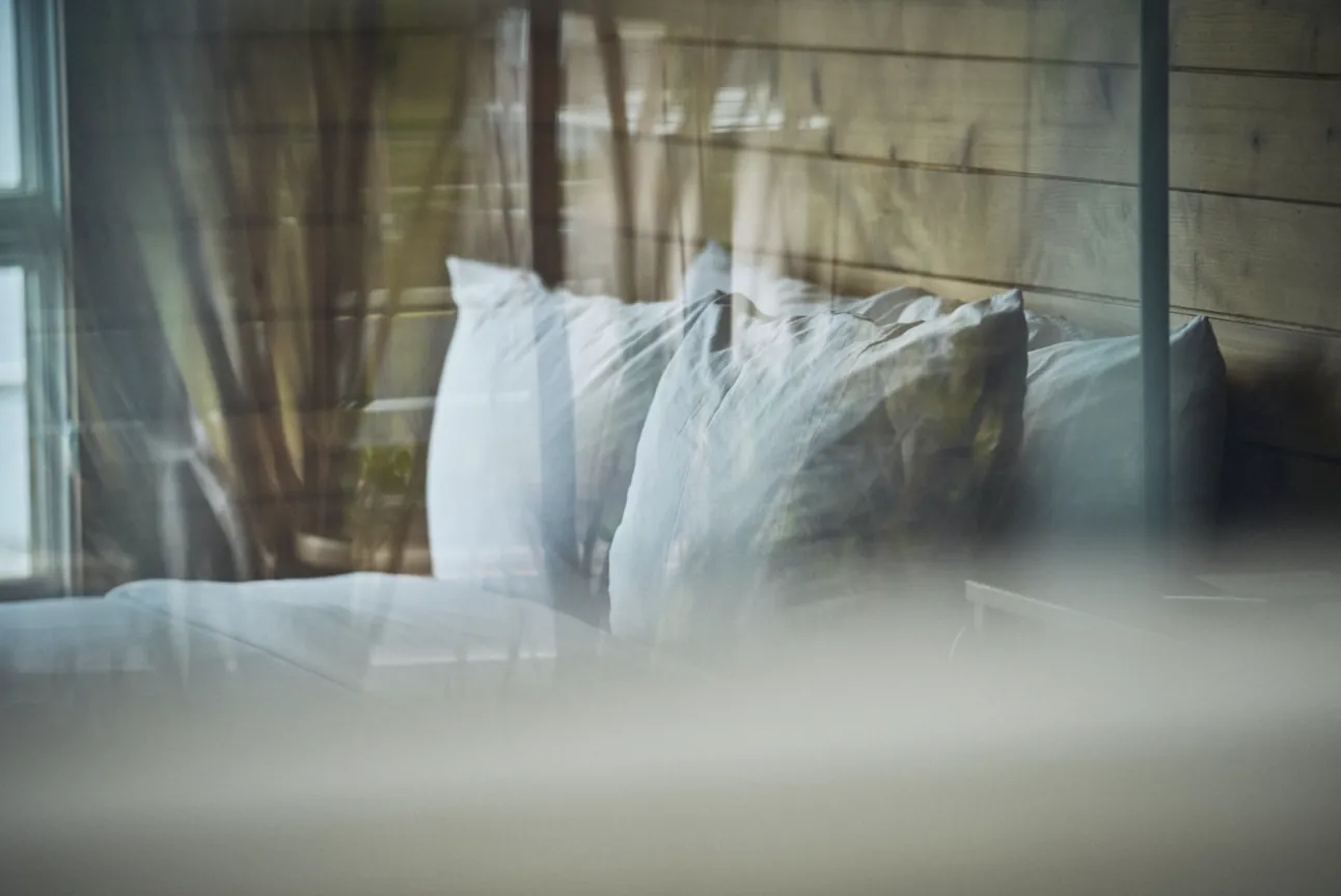 Soft pillows on a hotel bed seen through a window