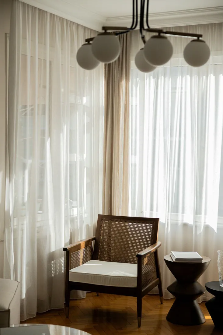 Sunlit hotel room corner with an armchair and globe pendant light