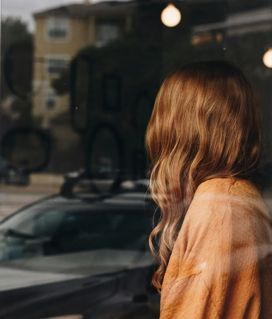 Guest with long hair looking out of a café window