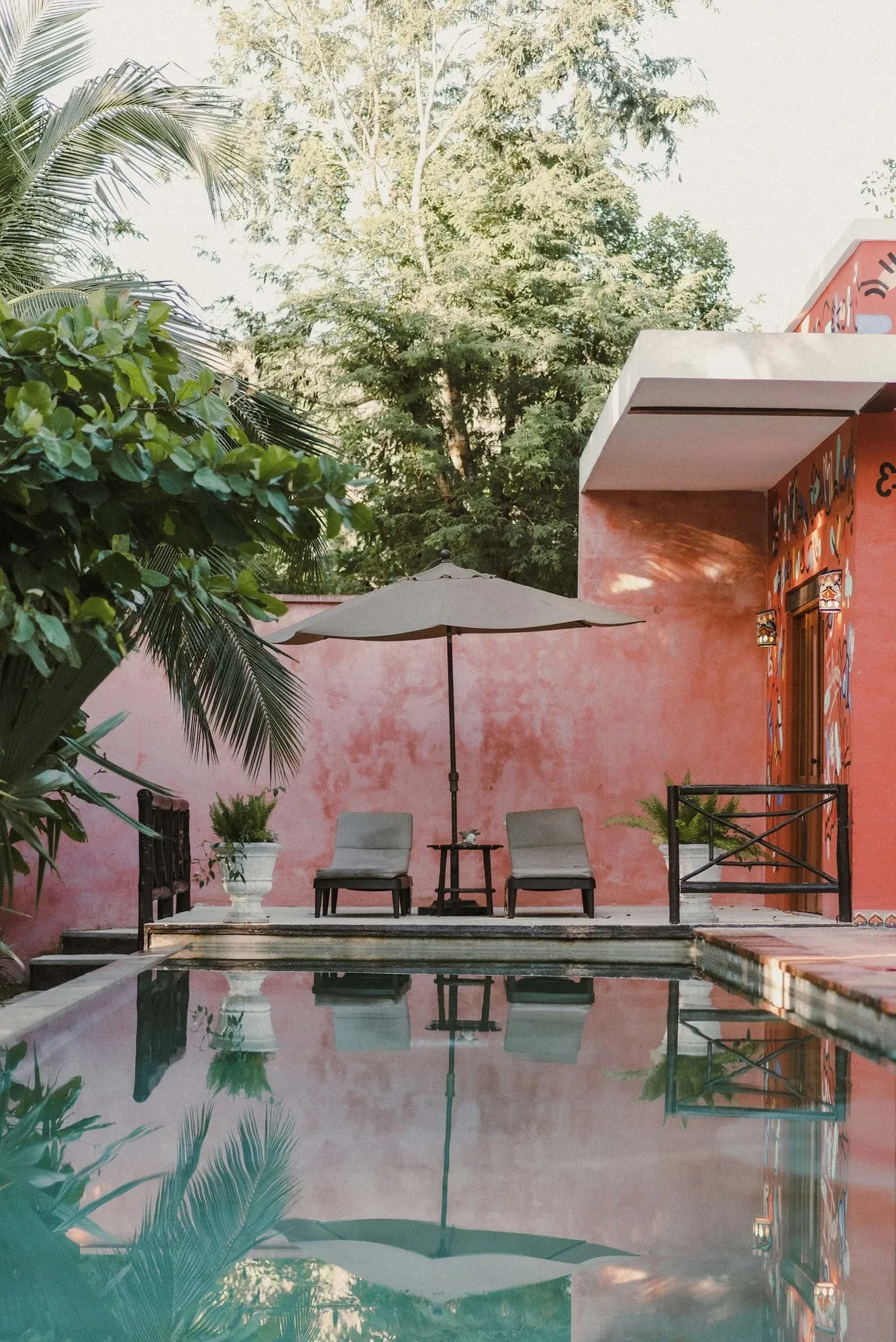 Pink hotel courtyard with a pool and umbrella