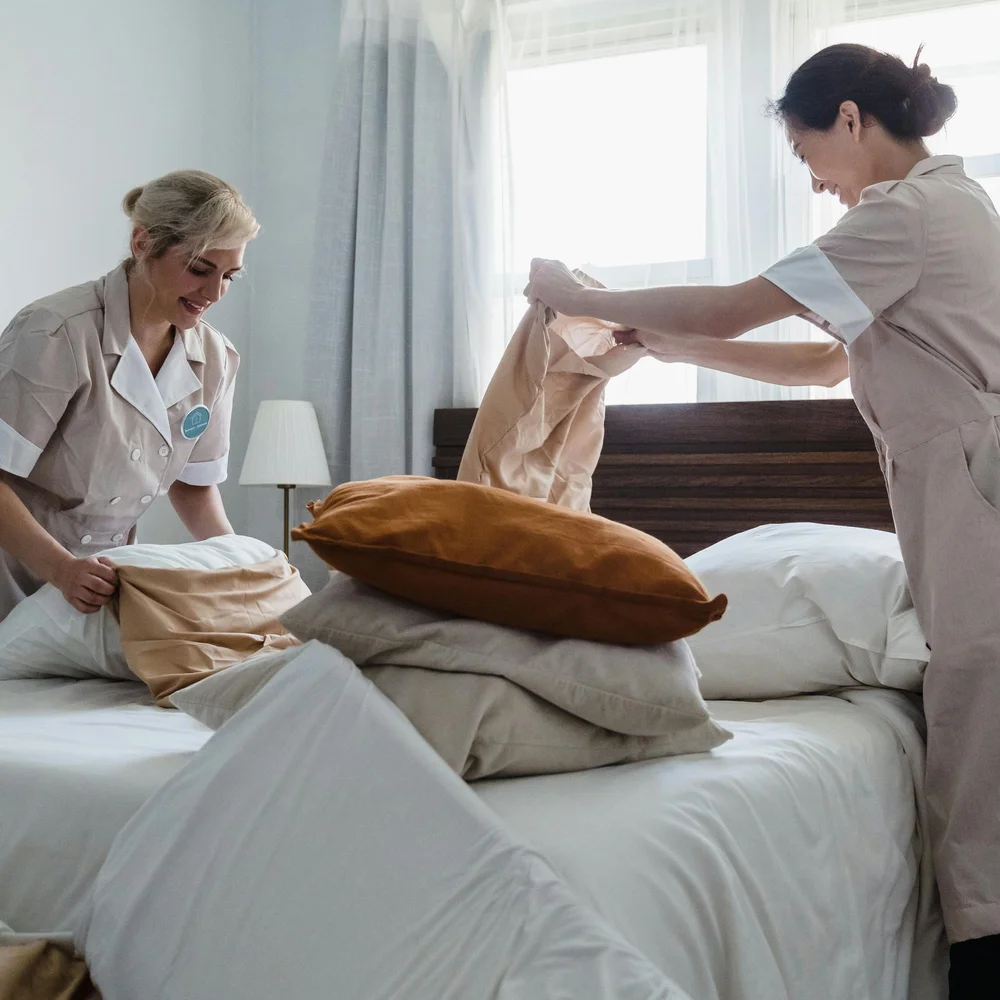 Two housekeepers making a hotel bed