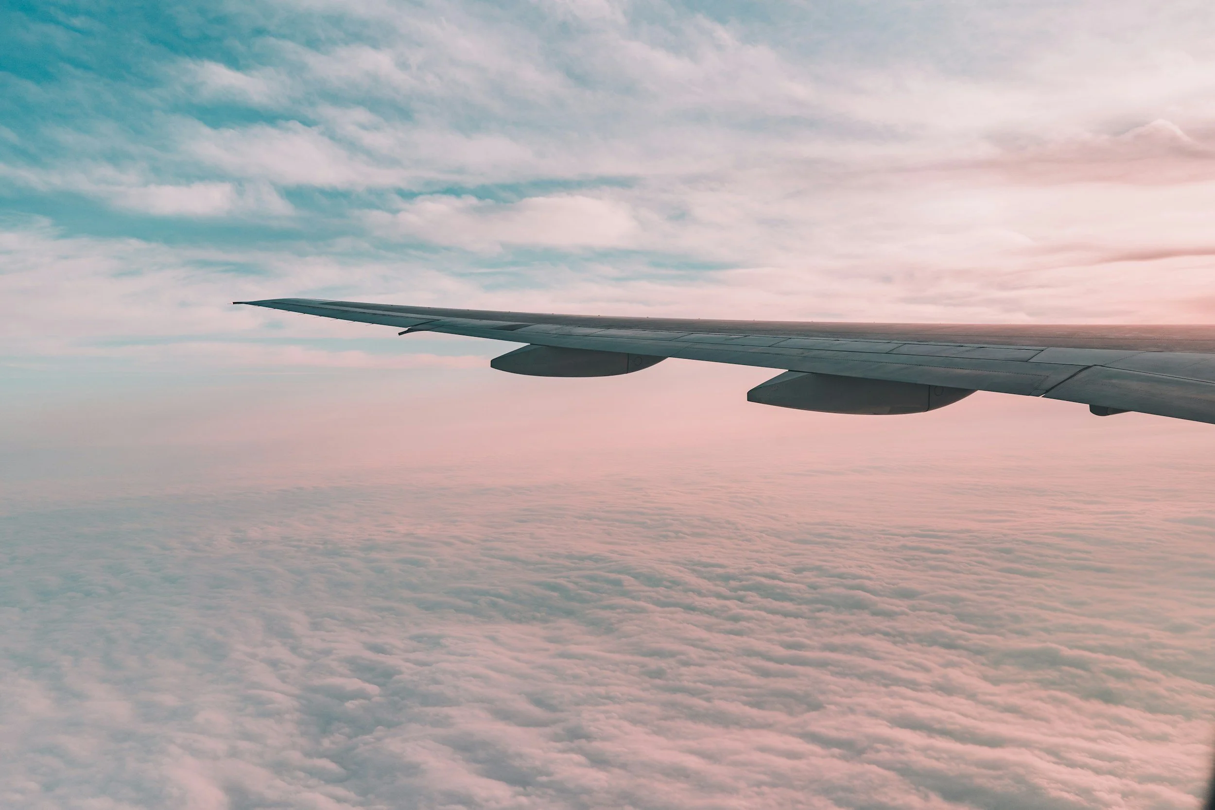 Airplane wing above pink clouds