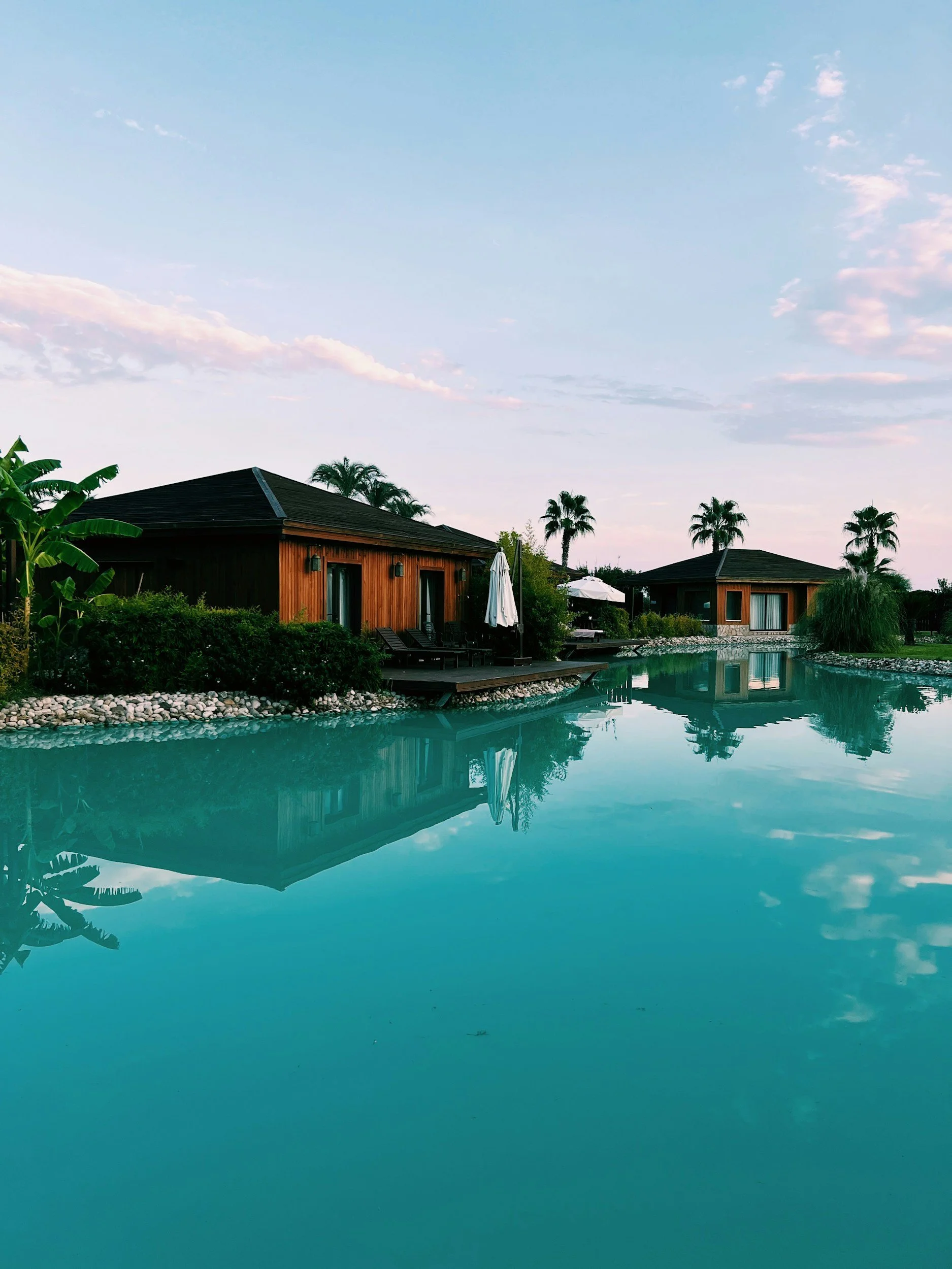Resort villas reflected in still water at dusk